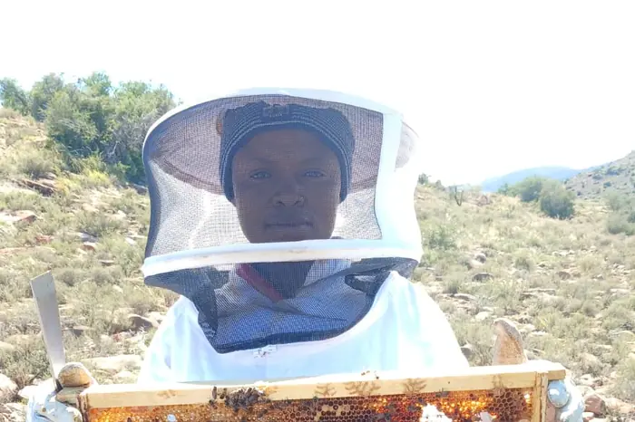 A beekeeper holding a frame of honeycomb